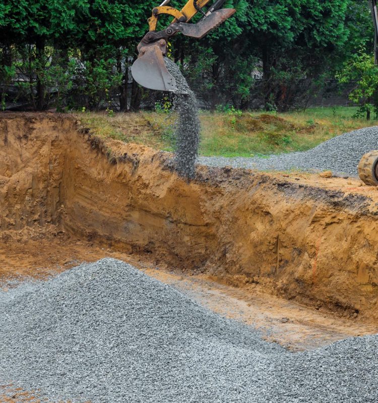 Backfilling trench for the gravel stones at construction site in excavator backfill of foundation Digger on a construction site